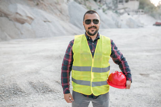 Worker in quarry standing in reflective clothing with headwear