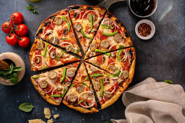 Sausage and vegetable pizza with pepperoni and mushrooms on dark background