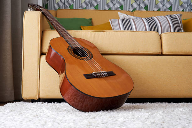 istock Classic guitar on the carpet close to the soft elegant yellow sofa 1349561638
