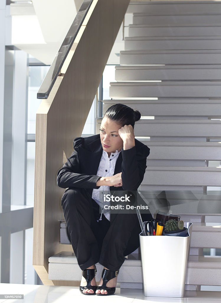 Fired female employee Downsizing, sad business woman Sitting on Stairs Being Fired Stock Photo