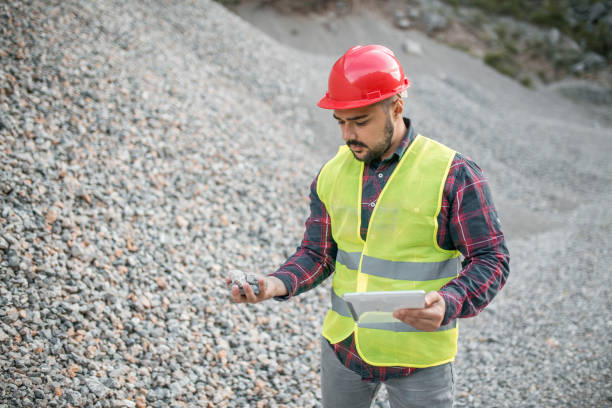 istock Engineer in quarry examining a stone he has found and holding digital tablet 1349576972
