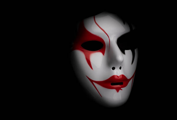 Scary mask for Halloween hand sprayed by photographer with dramatic lighting and black background
