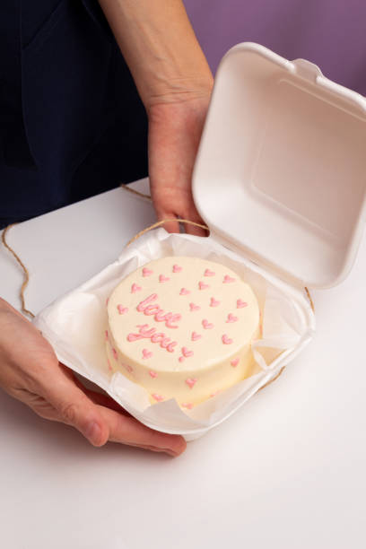 Bento cake with inscription "Love you" and hearts in plastic box-packaging. Selective focus. stock photo