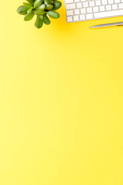 istock Elegant office desktop with computer keyboard and pen on yellow table. Business background with copyspace 1349583947