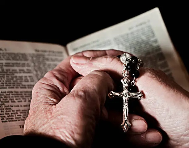 Close up of very old hands, holding a rosary,  clasped over an equally old  Bible. Faith in action. Shot with Canon EOS 1Ds Mark III.