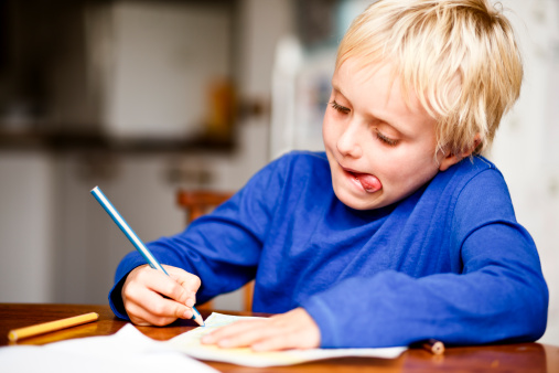 7 year old boy uses pencil crayons to make a picture, concentrating fiercely. Shot with Canon EOS 1Ds Mark III.