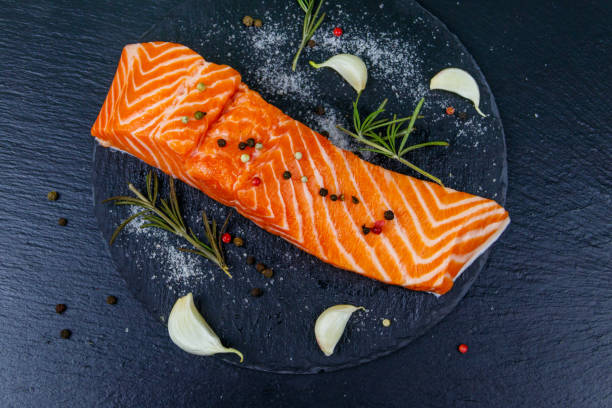 istock Raw salmon fillet with spices on black slate. Top view 1349588081