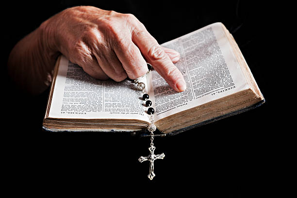 The Word of God An old woman's hands, holding rosary, read a verse from the Bible. Shot with Canon EOS 1Ds Mark III. nun praying cross human hand stock pictures, royalty-free photos & images