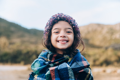 candid portrait of kid laughing while playing at summer park nature