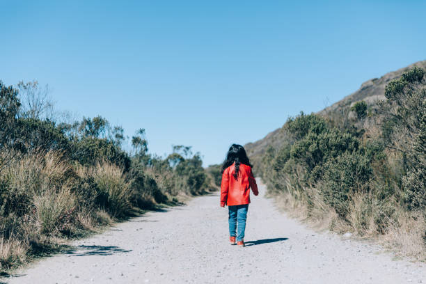 Young girl walking on an empty rural road