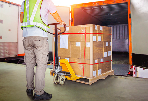 Worker Courier Unloading Package Boxes into Cargo Container. Delivery service. Truck Loading at Dock Warehouse. Shipments Supply Chain. Shipping Warehouse Logistics Transportation.