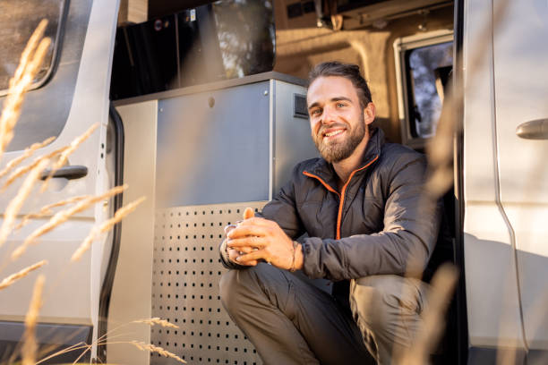 istock Smiling man sitting in his camper van 1349591837