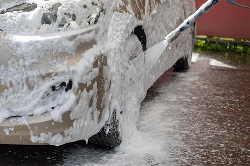 Car wash, car cleaning service, car wheel in shampoo foam