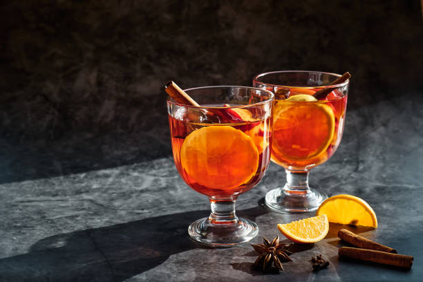 Wine glasses of hot mulled wine with spiced, apple and orange on dark background. Christmas traditional warming drink with cinnamon, cardamom and anise. Wine glasses of hot mulled wine with spiced, apple and orange on dark background. Christmas traditional warming drink with cinnamon, cardamom and anise. apple cinnamon pancake stock pictures, royalty-free photos & images