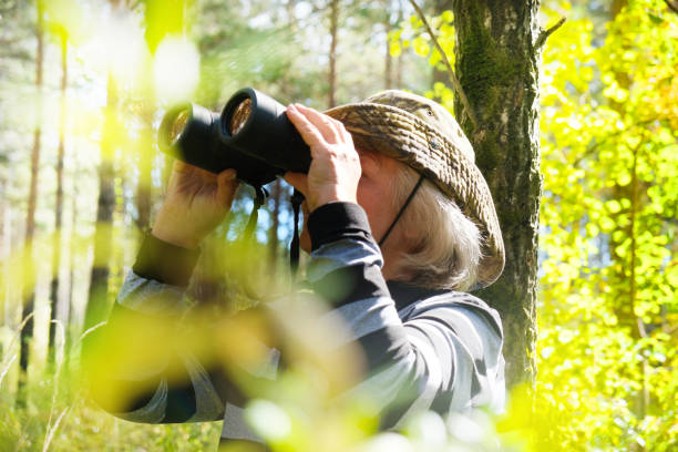 istock Active senior woman with binoculars in the forest 1349597737