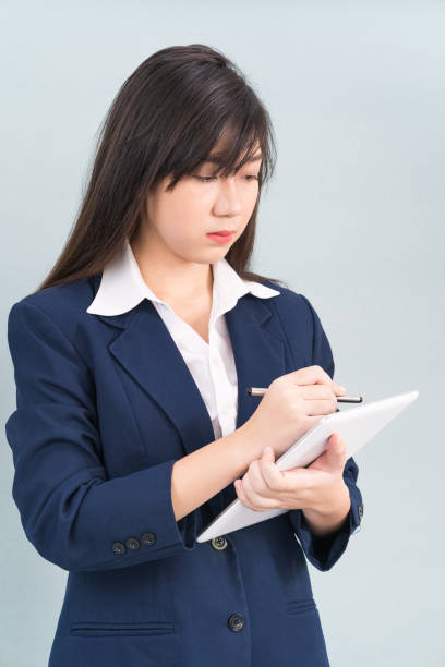 istock Woman in suit using digital tablet on gray background 1349597975