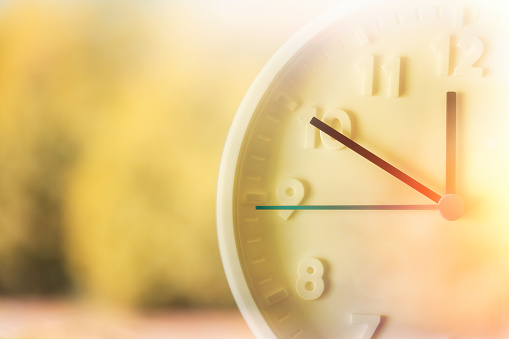 Blurred green background and close up of clock. Double exposure. Daylight Savings Time Concept.