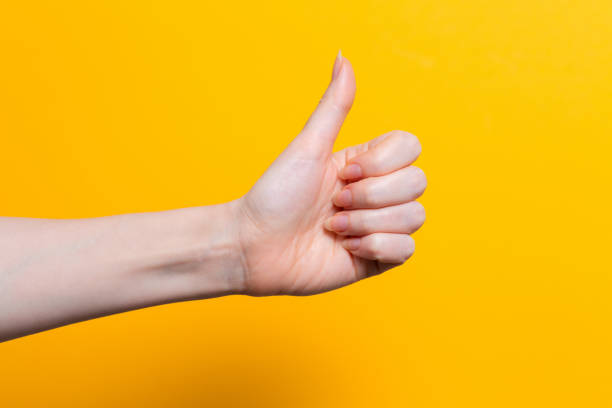 istock A woman's hand gives a thumbs up. Close up. Yellow background. Copy space 1349601092