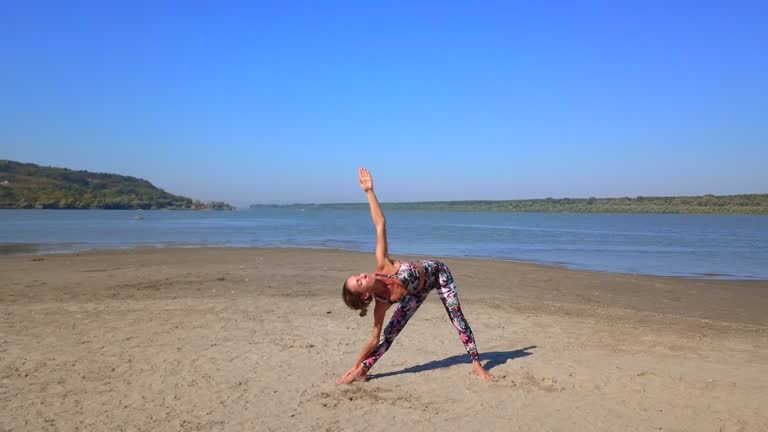 Woman doing yoga on sandy river shore