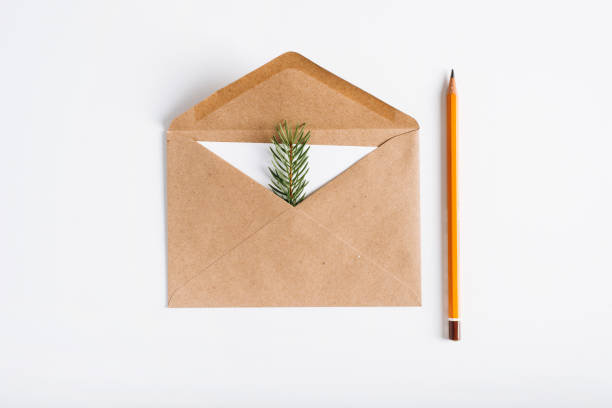 istock Christmas, Happy New Year minimal composition, flat lay. Top view open craft envelope, white card, pine twig and pencil on white table. Holiday message concept, greeting card 1349603504