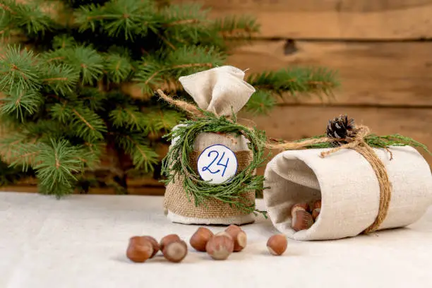 open box of Christmas advent calendar with hazelnuts made from eco materials on a wooden background with a Christmas tree.