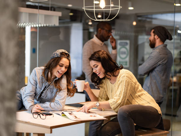 Happy creative women reading a magazine at casual office.
