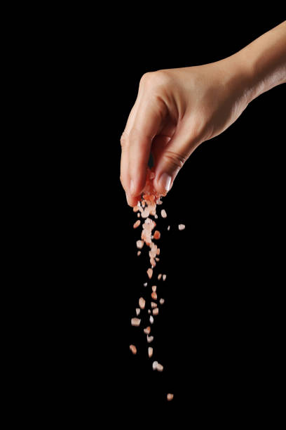 istock Hand sprinkle pink salt isolated on black background 1349608961