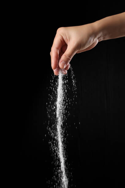 istock Hand sprinkling brown sugar isolated on black background 1349608963
