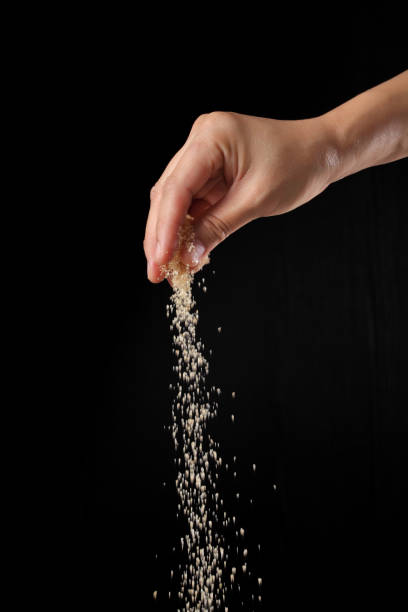 istock Hand sprinkling brown sugar isolated on black background 1349608964