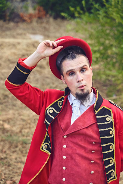 istock Man in fancy costume holding hat and looking at camera while standing on pavement during performance in park 1349610027