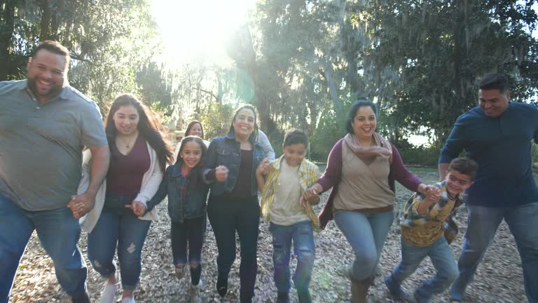 Multi-generation Hispanic family at park, sit on ground