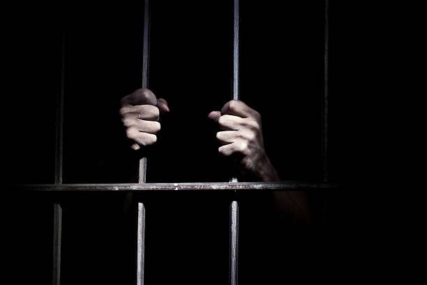 Hands of the prisoner Hands of the prisoner on a steel lattice close up jail stock pictures, royalty-free photos & images