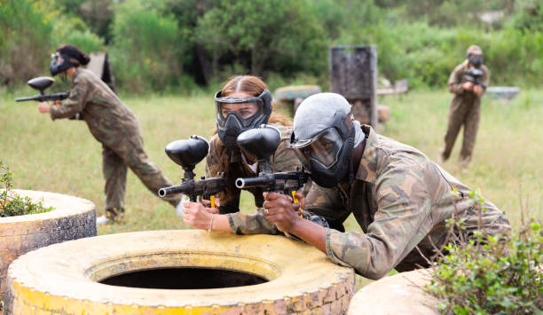 team von freunden paintballspieler, die zusammen im kampf spielen - paintball stock-fotos und bilder