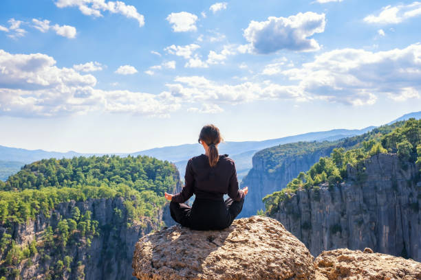istock Unrecognizable woman meditating on edge of cliff 1349643491