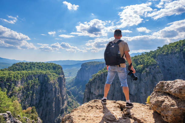 istock Faceless man with photo camera on cliff 1349643571
