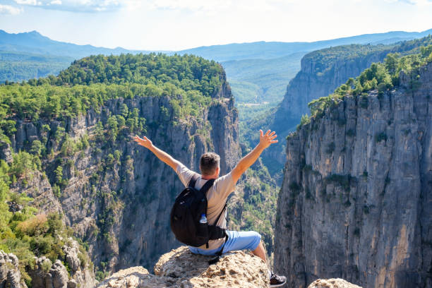 istock Unrecognizable man sitting on edge of cliff 1349646863