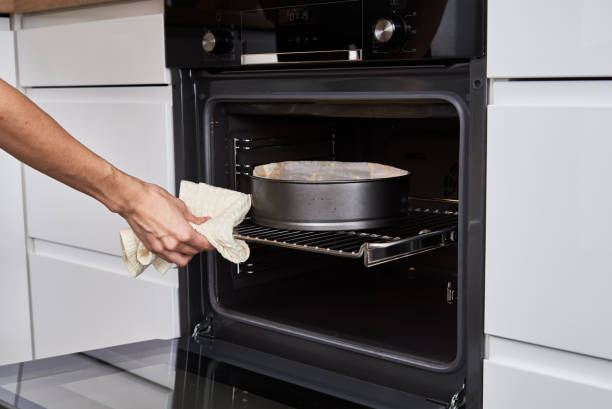 istock Woman cooking cake in electric oven 1349659300