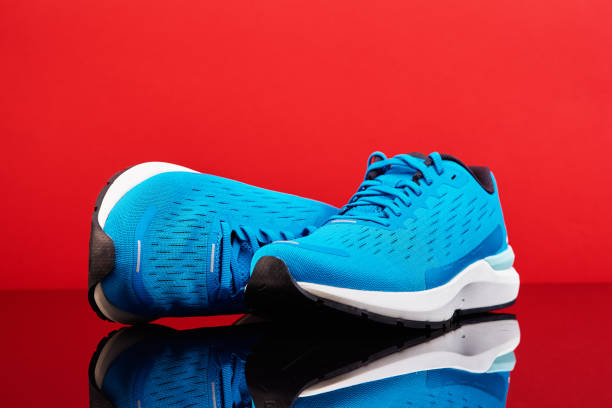 istock Pair of blue running sneakers on red background 1349659611