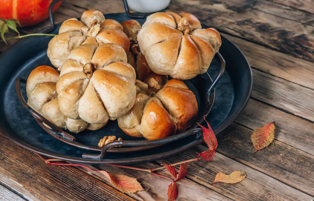 istock Pumpkin buns bread with cinnamon on retro tray over rustic wooden background. Autumn, Halloween food concept. 1349661021