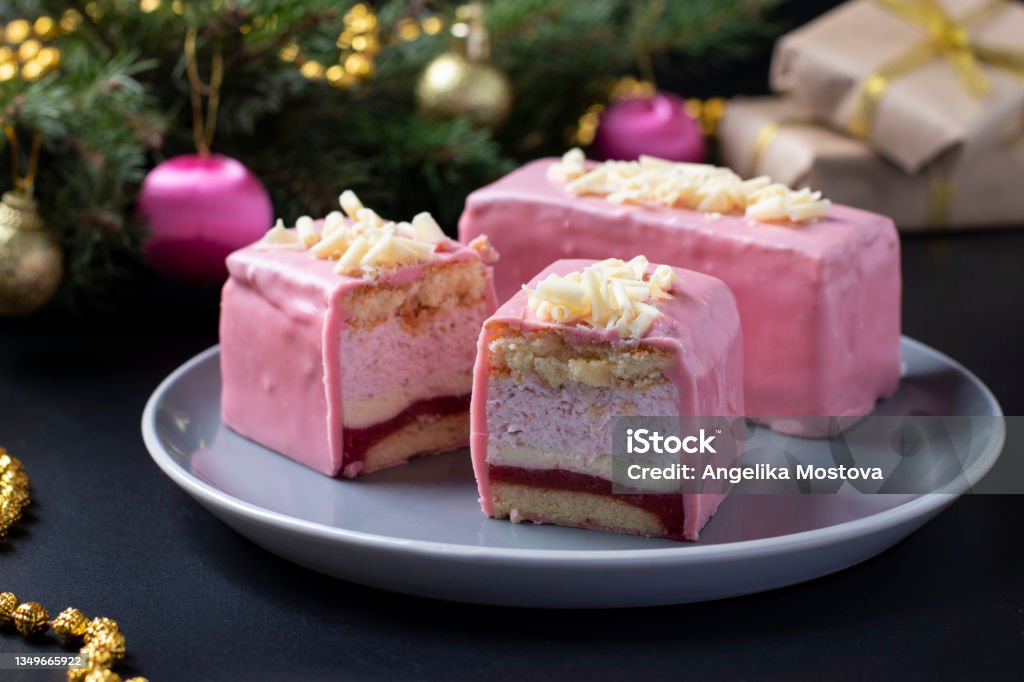 Sliced mousse desserts with almond biscuit, strawberry coolie and strawberry mousse covered gourmet pink chocolate glaze on new year background. Closeup Sliced mousse desserts with almond biscuit, strawberry coolie and strawberry mousse covered gourmet pink chocolate glaze on new year background. Almond Stock Photo