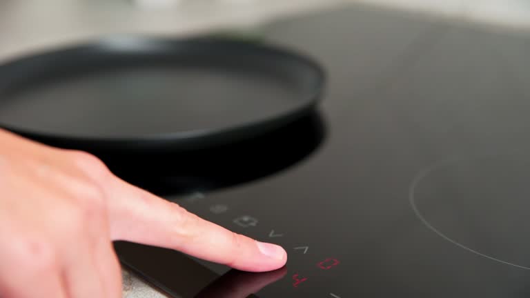 Woman hand turns on modern induction stove in the kitchen