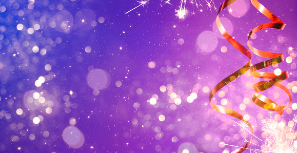Celebration party background with a golden streamer, glitter, sparkler, sparks and lights bokeh