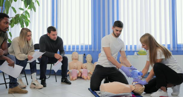 istock Group of people with instructor practicing CPR on mannequin at first aid class indoors. 1349670845