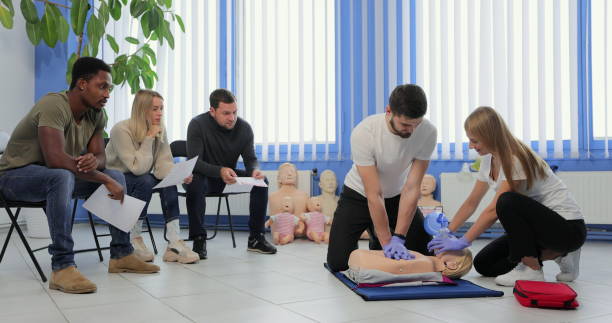 instrutor masculino ensinando técnica de rcp de primeiros socorros para seus alunos. - cpr - fotografias e filmes do acervo