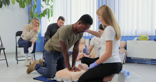 istock Young woman instructor showing how to make chest compressions with dummy during the first aid group training indoors. 1349670891