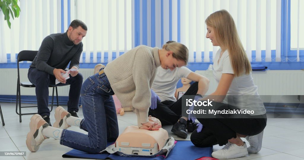 Woman demonstrating CPR on mannequin in first aid class. Woman demonstrating CPR on mannequin in first aid class First Aid Class Stock Photo