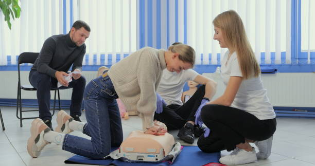 Woman demonstrating CPR on mannequin in first aid class. Woman demonstrating CPR on mannequin in first aid class first aid class stock pictures, royalty-free photos & images
