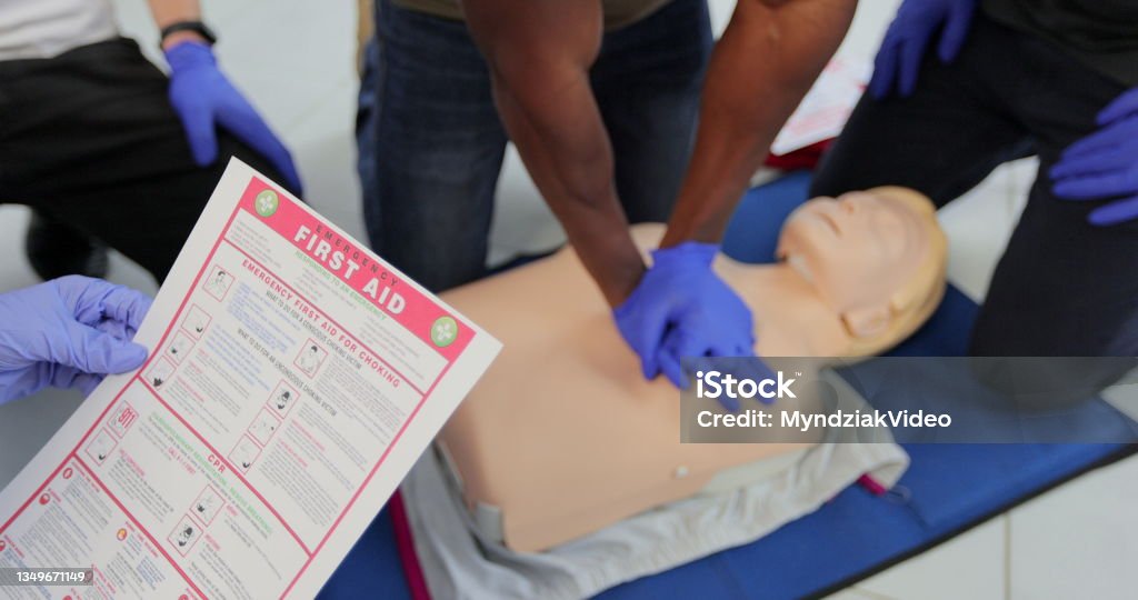 CPR First Aid training concept. Back view of woman holding first aid instruction during cpr training class. CPR First Aid training concept. Back view of woman holding first aid instruction during cpr training class CPR Stock Photo