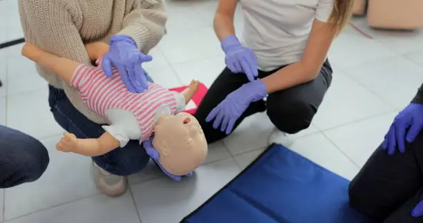 Closeup of first aid instructor using infant dummy demonstrating how to rescue a suffocating baby