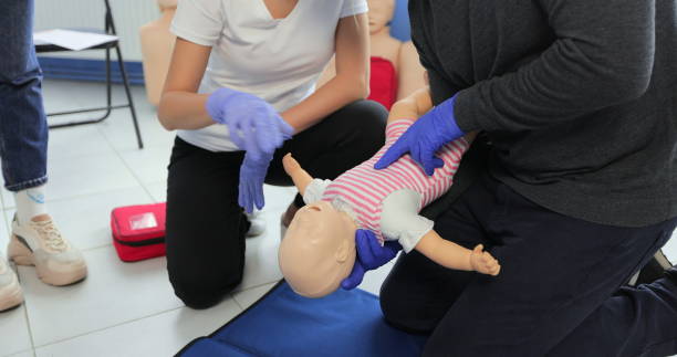 istock Closeup man learning how to make chest compressions on a baby dummy during the first aid group training indoors. 1349671441